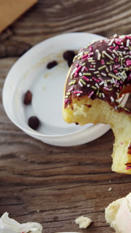 Lipstick-mark-on-coffee-cup-and-half-eaten-chocolate-doughnut-with-sprinkles