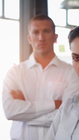 Business-executives-standing-with-arms-crossed-in-office