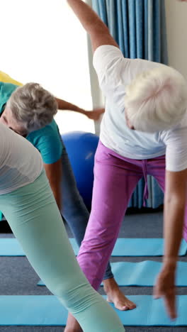 Trainer-assisting-senior-citizens-in-performing-stretching-exercise