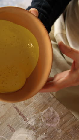 Male-potter-mixing-watercolor-in-bowl-at-pottery-workshop