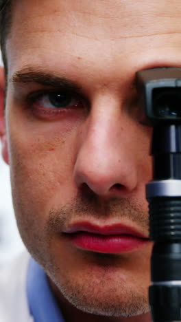 Close-up-of-optometrist-looking-through-ophthalmoscope