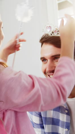 Girl-dressed-up-in-a-fairy-costume-placing-tiara-on-fathers-head