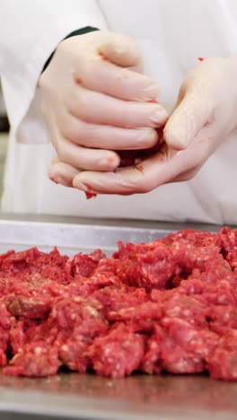 Mid-section-of-butcher-preparing-meat-ball-from-minced-meat