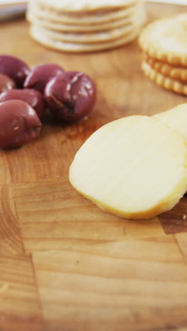 Slices-of-bread,-crackers,-olives,-walnut-and-knife-on-wooden-board