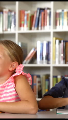 School-kids-raising-hand-in-library