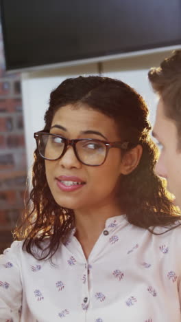 Businesswoman-interacting-with-coworkers-while-working-on-computer