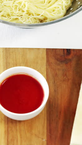 Cheese-slice-and-sauce-on-cutting-board-with-boiled-pasta