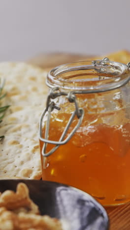 Bowl-of-green-olives,-bread,-jam,-rosemary-herb,-cheese-and-walnuts-on-wooden-board