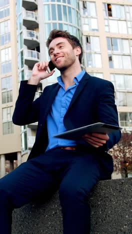 Businessman-talking-on-mobile-phone-and-holding-digital-tablet