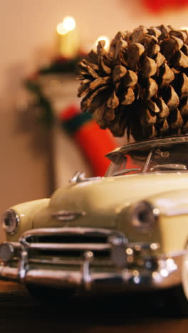 Toy-car-with-pine-cone-on-wooden-table