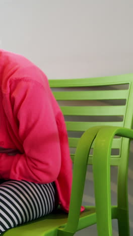 Upset-girl-sitting-on-chair-in-hospital-corridor