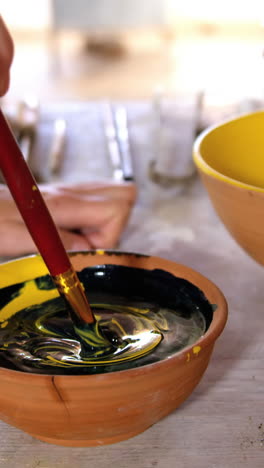 Hands-of-female-potter-mixing-paint-into-bowl