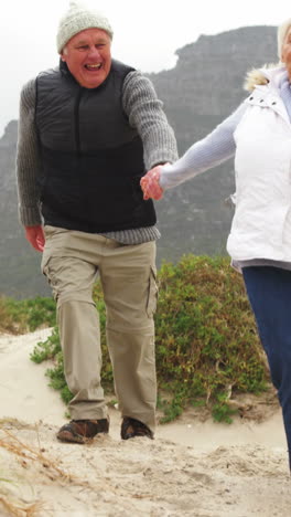 Senior-couple-holding-hands-and-walking-on-the-beach