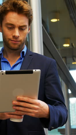 Businessman-holding-coffee-cup-and-using-digital-tablet