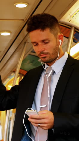 Businessman-using-mobile-phone-while-listening-to-music