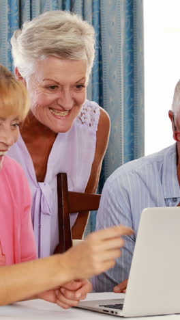 Female-volunteer-and-senior-citizens-using-laptop