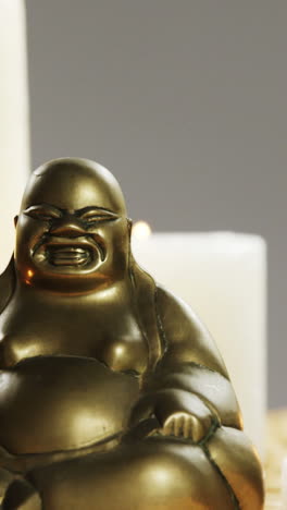 Close-up-of-laughing-buddha-figurine-with-burning-candles