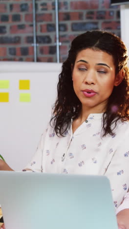 Businesswoman-interacting-with-coworker-while-working-on-computer