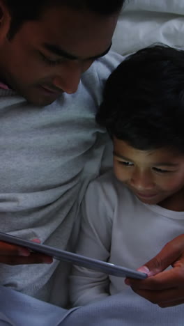 Vater-Und-Sohn-Nutzen-Digitales-Tablet-Auf-Dem-Bett