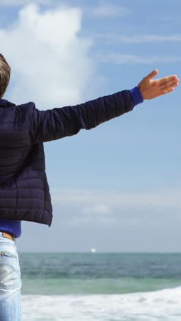 Mature-man-standing-with-arms-outstretched-on-the-beach