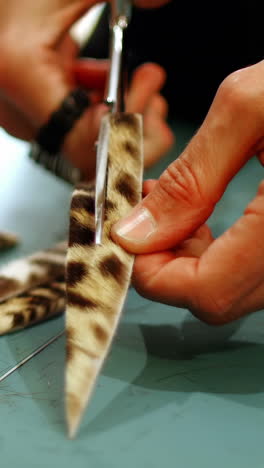 Mid-section-of-craftswoman-cutting-leather-with-scissors