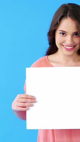 Beautiful-woman-holding-blank-placard-on-blue-background