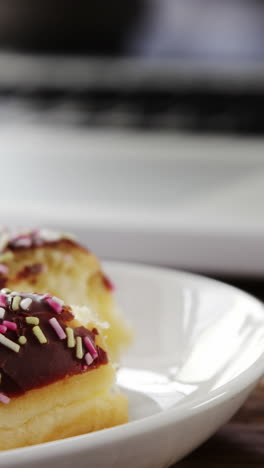 Half-eaten-chocolate-doughnut-with-sprinkles-on-wooden-table