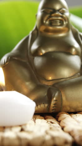 Close-up-of-laughing-Buddha-figurine-with-pebble-stone