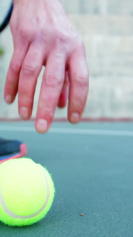 Man-picking-up-tennis-ball