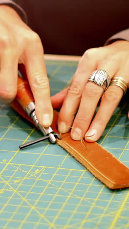 Mid-section-of-craftswoman-cutting-leather