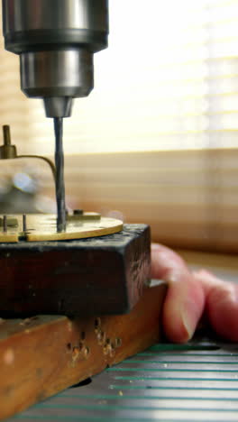 Horologist-using-drill-machine-on-a-clock-part