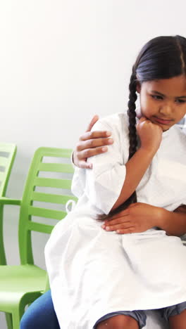 Mother-talking-on-mobile-phone-while-girl-sits-on-her-lap