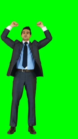 Businessman-standing-with-arms-up-against-green-background