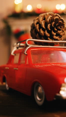 Toy-car-with-pine-cone-on-wooden-table