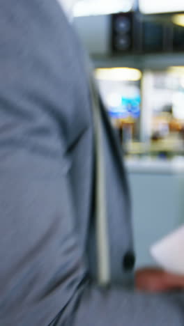 Businessman-using-mobile-phone-while-checking-his-boarding-pass