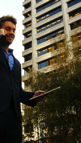 Businessman-talking-on-mobile-phone-and-holding-digital-tablet