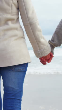 Couple-holding-hands-and-walking-on-beach