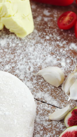 Rolling-pin-with-pizza-dough,-flour,-vegetables-and-spices-on-plate