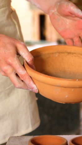 Male-potter-checking-bowl-in-pottery-workshop