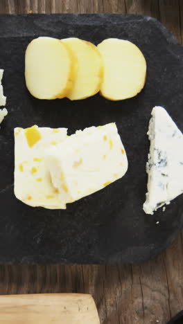 Variety-of-cheese,-olives,-biscuits-and-rosemary-herbs-on-wooden-table