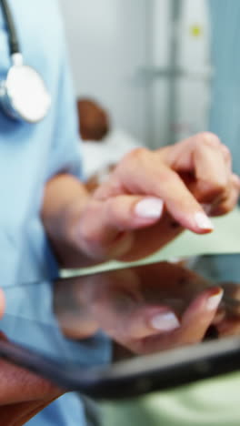 Mid-section-of-female-doctor-using-digital-tablet