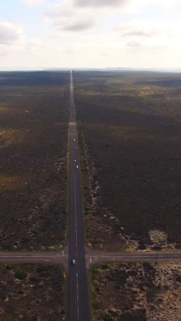 Aerial-view-of-a-dirt-road-winding-around-rural-field-