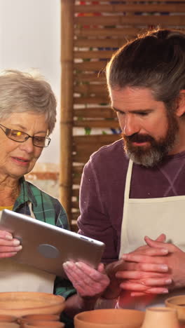 Male-and-female-potter-using-digital-tablet