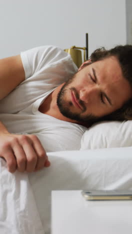 Man-checking-his-mobile-phone-in-bedroom