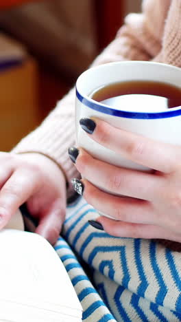 Frau-Liest-Einen-Roman,-Während-Sie-Im-Wohnzimmer-Kaffee-Trinkt