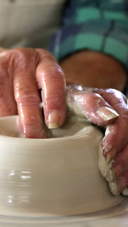 Mid-section-of-female-potter-making-pot