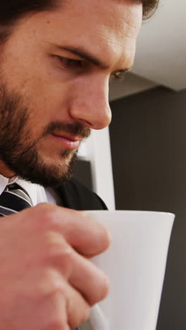 Businessman-reading-newspaper-while-having-coffee-in-kitchen