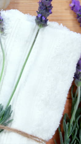 Wooden-bowl-with-lavender-petals,-pebble-stone,-oil-bottle-and-towel