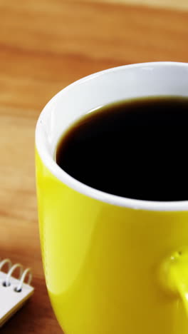 Coffee-mug,-notepad-and-pencil-on-wooden-plank