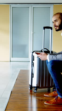 Businessman-texting-on-mobile-phone-at-airport